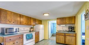 a kitchen with wooden cabinets and a white refrigerator at The Driftwood in Old Orchard Beach