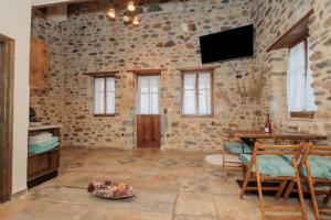 a room with a stone wall with a table and a television at Mystras Panorama House in Mystras