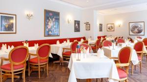 a dining room with white tables and red chairs at Hotel Döllnsee-Schorfheide in Templin