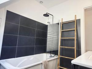 a bathroom with a white tub and a black tile wall at Appartement au port Le Mont-Saint-Michel in Dinan