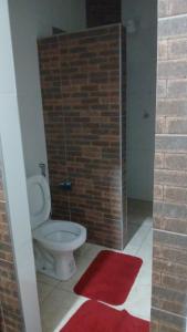 a bathroom with a toilet and a brick wall at Espaço MV Family in Prado +18 photos