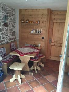 einen Tisch und Bänke in einem Zimmer mit einer Steinmauer in der Unterkunft Maso Toneto in Castello di Fiemme