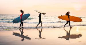 three women walking on the beach with their surfboards at Ma case créole in Port-Louis