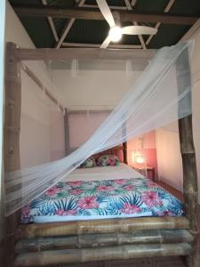a bed with a mosquito net in a room at Ma case créole in Port-Louis