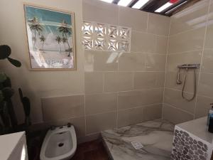a bathroom with a toilet and a picture of palm trees at Ma case créole in Port-Louis