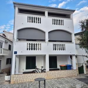 a white house with a bike parked in front of it at Roko Apartments in Biograd na Moru