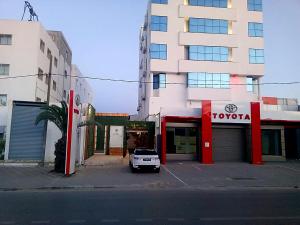 a car parked in a parking lot in front of a building at Les persiennes usées in Sfax