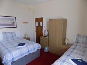 a bedroom with two beds and a wooden cabinet at Belle View in Skegness