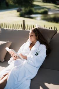 a woman sitting on a couch reading a book at Ritzenhof - Hotel und Spa am See 4-Sterne-Superior in Saalfelden am Steinernen Meer +96 photos