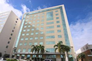 a tall building with palm trees in front of it at Quarto Economico Hotel - Complexo Prima cittá ao lado do Shoping Patio Mix in Linhares