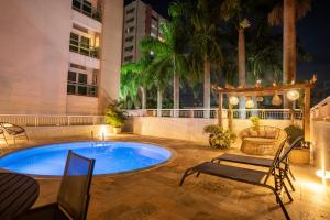 a pool in a courtyard with chairs and a building at Hotel Cianorte Diamond in Cianorte