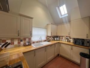 a kitchen with white cabinets and a sink at Heron's Hideaway in Wells next the Sea