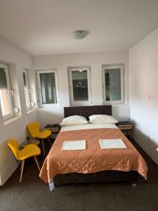 a bedroom with a bed and two yellow chairs at Hotel Avanti in Zenica