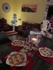 a table with food and wine glasses and a christmas tree at Sabry house in Novi Ligure