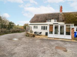 a white cottage with a thatched roof at Long Barn in Bridport