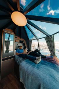 a couple laying on a bed in a room with a window at Adventure Stay in Vík