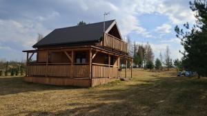 a large wooden cabin with a black roof at Domki Dębowe Wzgórze in Potok Złoty
