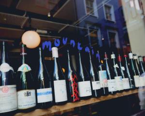 a bunch of bottles of wine on a shelf at Otherwander Soho Pod Hotel in London