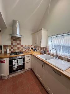 a kitchen with a sink and a stove at Heron's Hideaway in Wells next the Sea +2 photos