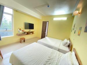 a hotel room with two beds and a television at Hi Hotel in Kỳ Vĩ