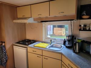a small kitchen with a sink and a window at Gezellig chalet voor gezinnen op de Veluwe I Veldkamp F16 in Epe