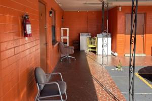 a room with two chairs and an orange wall at Stevens Motel by Capital O Ocala US 27 in Ocala +19 photos