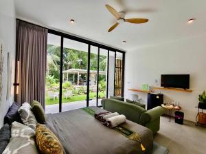 a bedroom with a bed and a couch and a ceiling fan at Villa harmony haven in Taling Ngam in Ban Khok Kroat