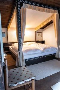 a bedroom with a canopy bed and a chair at Berghotel Blaickner's Sonnalm in Zell am See