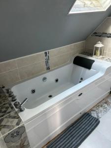 a large white bath tub in a bathroom at Gîte spacieux, Proche Plage, Grand jardin in Neufchâtel-Hardelot