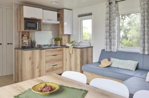 a kitchen and living room with a table and a blue couch at Camping Bel Air - Cancale in Cancale