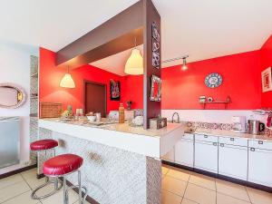 a large kitchen with red walls and red stools at Holiday Home Gevanac by Interhome in Crozon