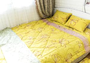 a bed with a yellow comforter and pillows at Homestay Eve in Seoul