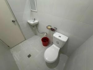 a white bathroom with a toilet and a sink at Belga Boarding House in Guimaras