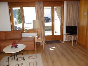 a living room with a couch and a tv at Apartment Blumenweg 6 by Interhome in Engelberg +9 photos