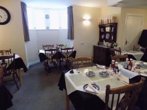 a dining room with tables and chairs and a clock at Belle View in Skegness +20 photos