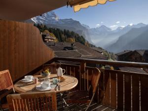 a table on a balcony with a view of mountains at Apartment Bella Vista Apt- No- 09 by Interhome in Wengen