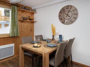 a dining room table with chairs and a clock on the wall at Apartment Baroudeur B04 by Interhome in Verbier +25 photos