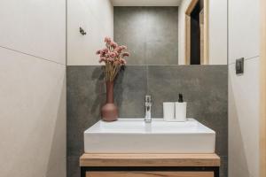 a bathroom with a white sink and a vase with flowers at Apres Ski Bachleda in Zakopane