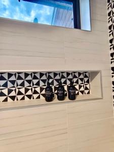 a bathroom with three black bottles on a wall at Villa harmony haven in Taling Ngam in Ban Khok Kroat
