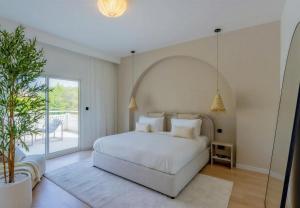a bedroom with a white bed and a large window at Villa Mansour in Abu Dhabi