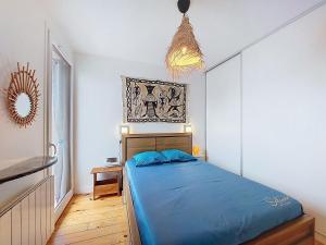 a bedroom with a blue bed and a chandelier at Apartment la Pergola-2 by Interhome in Soorts-Hossegor
