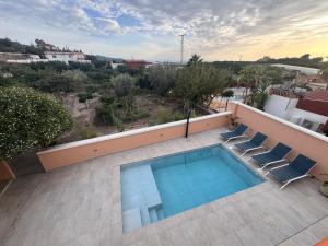 a swimming pool on top of a building with two chairs at Comeback Villa Itaca in Motril