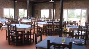 a dining room with tables and chairs and windows at Camping Palacio de Garaña in Garaña