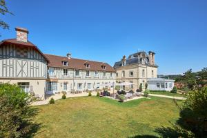 ein großes Herrenhaus mit einem großen Rasengarten in der Unterkunft Les Villas d'Arromanches, Teritoria in Arromanches-les-Bains