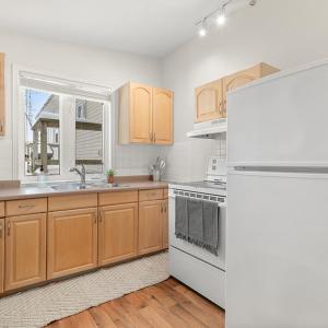 a kitchen with wooden cabinets and a white refrigerator at Newsroom Suites in Wellington