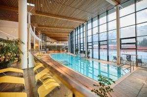 a large swimming pool with yellow chairs in a building at Pension Speckmoser in Bad Mitterndorf