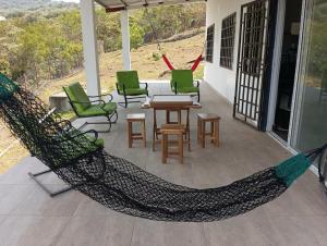 a hammock on a porch with chairs and a table at Boca de viento Chica in Chicá