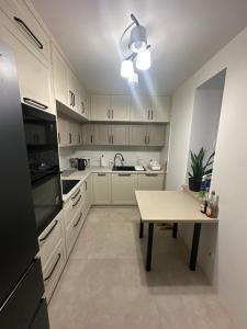 a kitchen with white cabinets and a table in it at Apartament rodzinny in Łańcut