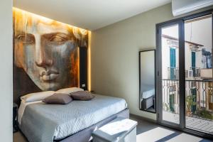 a bedroom with a painting of a face on the wall at Dea's Rooms in Noto