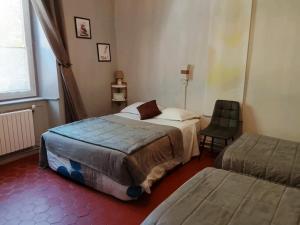 a hotel room with two beds and a chair at Auberge Cocagne in Avèze